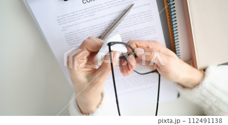 Female hands wiping eyeglasses with napkin at table closeup Female hands wiping eyeglasses with napkin at table closeup 112491138