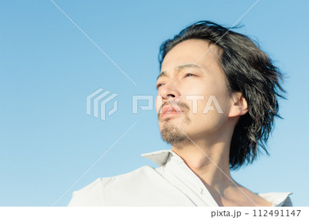 海辺に佇む白シャツを着た30代男性 海辺に佇む白シャツを着た30代男性 112491147