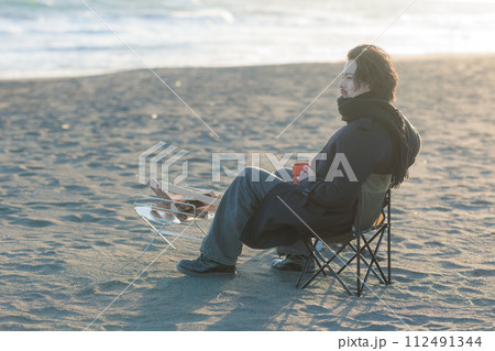 海辺て焚き火をする30代男性 112491344