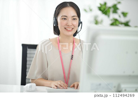 ヘッドフォンをつけて仕事をする若いオペレーター ヘッドフォンをつけて仕事をする若いオペレーター 112494269
