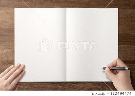 テーブルの上にあるノートに字やイラストを書く手の背景テクスチャー 112494474