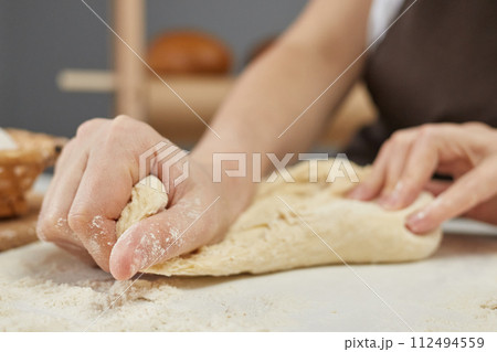 The process of preparing dough for baking bread, unrecognizable female kneading dough for making whole grain pastry 112494559