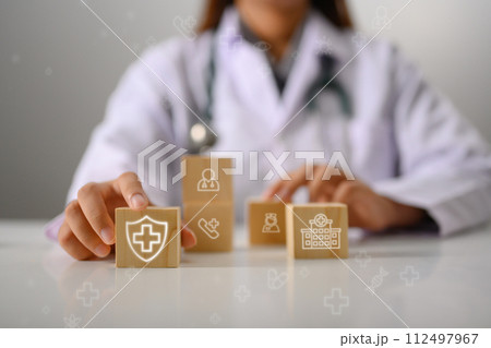 Doctor's hand touching wooden cubes with medical icon. Health Insurance concept 112497967