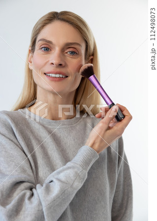 Pretty young blonde woman doing make up and smiling Pretty young blonde woman doing make up and smiling 112498073