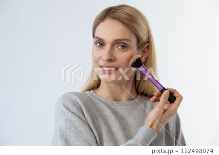 Pretty young blonde woman doing make up and smiling 112498074
