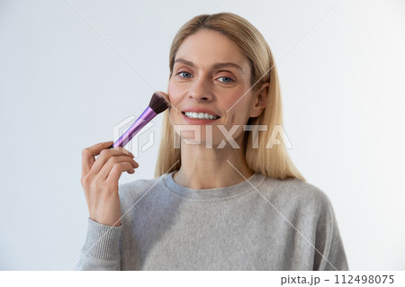 Pretty young blonde woman doing make up and smiling 112498075