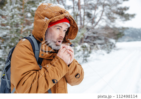 Man in warm jacket getting cold in a winter forest Man in warm jacket getting cold in a winter forest 112498114
