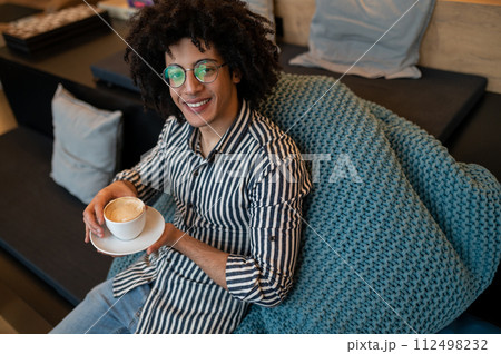 Top view of a young curly-haired man having coffee and smiling 112498232