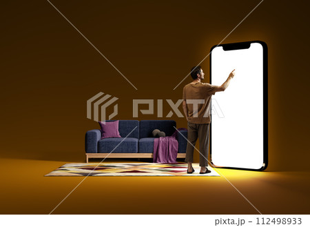Smiling man in home wear standing in room and pointing at big mobile phone screen, using online services for shopping and delivery services. 3D model of phone 112498933