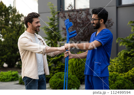 Man with crutches talking to a doctor and feeling excited 112499594