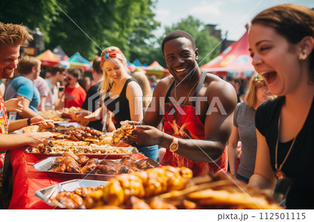 Group of happy friends share a laugh over grilled food at a sunny outdoor festival 112501115