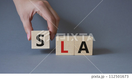 SLA - Service Level Agreement. Wooden cubes with word SLA. Businessman hand. Beautiful grey background. Business and Service Level Agreement concept. Copy space. 112501673