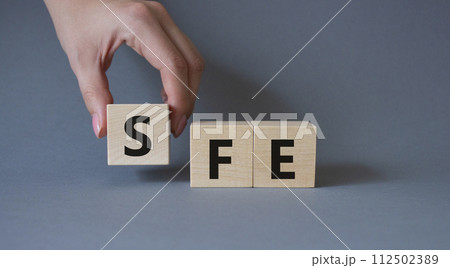 SFE - Sales Force Effectiveness. Wooden cubes with word SFE. Businessman hand. Beautiful grey background. Business and Sales Force Effectiveness concept. Copy space. SFE - Sales Force Effectiveness. Wooden cubes with word SFE. Businessman hand. Beautiful grey background. Business and Sales Force Effectiveness concept. Copy space. 112502389