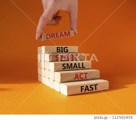 Dream Big Start Small Act Fast symbol. Concept words Dream Big Start Small Act Fast on wooden blocks. Businessman hand. Beautiful orange background. Business concept. Copy space. 112502459