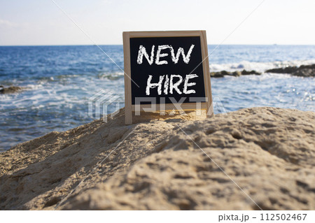 New Hire symbol. Concept words New Hire on black chalk background. Beautiful sea background. Business and New Hire concept. Copy space. New Hire symbol. Concept words New Hire on black chalk background. Beautiful sea background. Business and New Hire concept. Copy space. 112502467