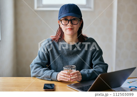 グラスを持つカメラ目線の若い女性 112503099