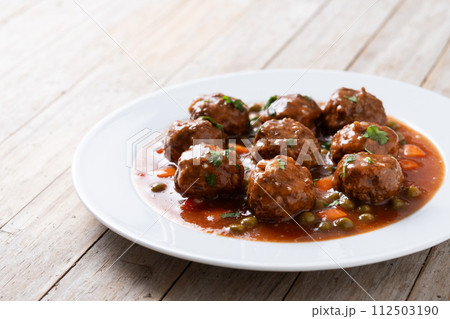Meatballs, green peas and carrot with tomato sauce on wooden table 112503190