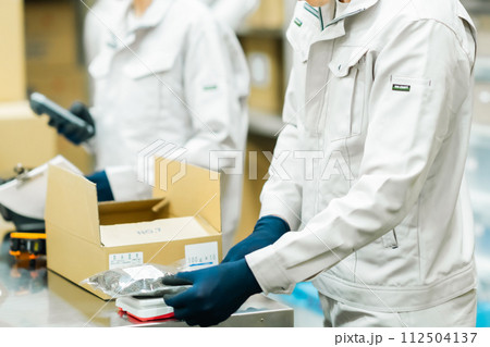 バックヤードでラベリングをする若い作業員 顔無し バックヤードでラベリングをする若い作業員 顔無し 112504137