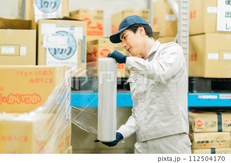出荷前にラッピングをする若い作業員 112504170
