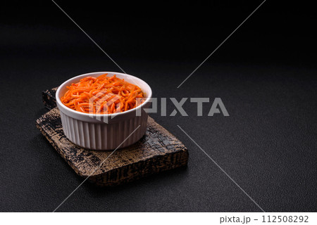 Tasty spicy Korean carrot with spices and herbs on a dark concrete background 112508292