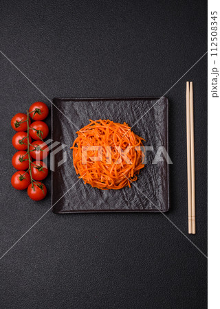 Tasty spicy Korean carrot with spices and herbs on a dark concrete background Tasty spicy Korean carrot with spices and herbs on a dark concrete background 112508345