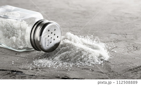 Salt glass jar and pile of spilled salt on a concrete plate Salt glass jar and pile of spilled salt on a concrete plate 112508889