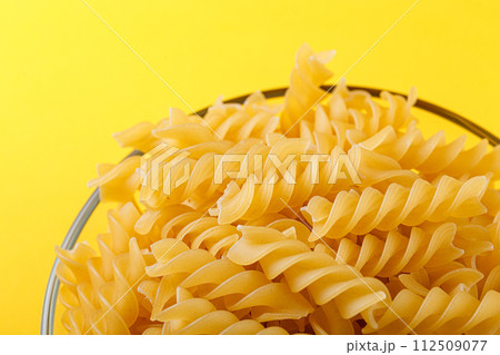 Different types and shapes of dry italian pasta on a yellow background 112509077