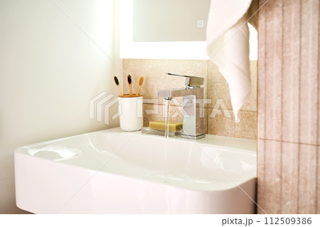 Bathroom sink with toothbrushes and running water. 112509386