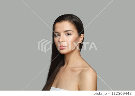 Stylish female model with long perfect hair and clean skin posing on gray studio wall background 112509448