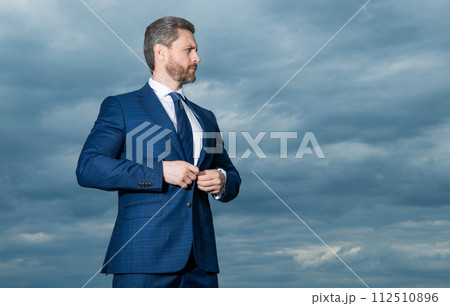 Professional man sky background. Grizzled man buttoning suit. Serious man looking aside, copy space 112510896