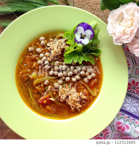 Green plate with delicious soup with small meatballs, peppers and spices on a wooden background and patterned tablecloth. AI-generated item Green plate with delicious soup with small meatballs, peppers and spices on a wooden background and patterned tablecloth. AI-generated item 112511005