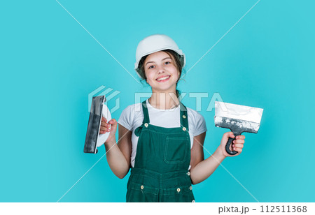 teen girl plasterer in protective helmet use spatula, plastering 112511368