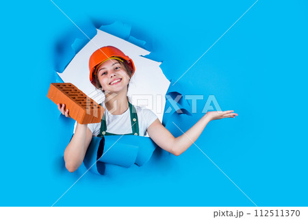happy kid engineer with brick in hard hat, work tool, presenting product happy kid engineer with brick in hard hat, work tool, presenting product 112511370