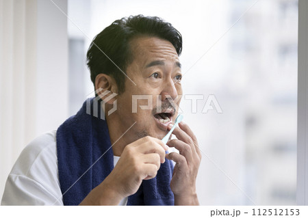 歯磨きをしながら歯茎を気にする50代の男性 112512153
