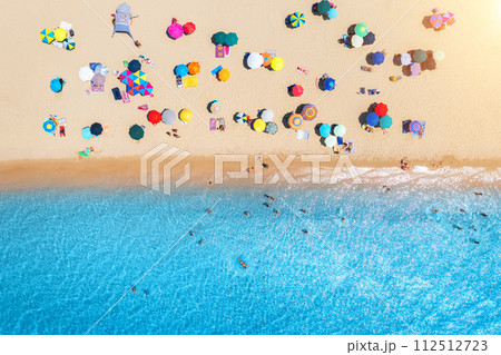 Aerial view of umbrellas on white sandy beach, blue sea at sunset 112512723