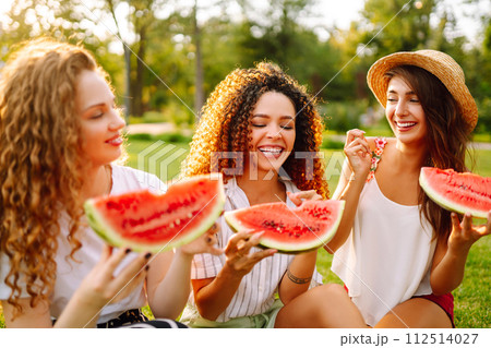 Three young woman have fun together and eating watermelon in hot summer day. 112514027