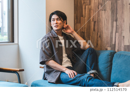 ソファで退屈な時間を過ごす若いアジア人男性（アンニュイ・まらない・憂鬱・無気力・ダルい・疲労・怒る） 112514570