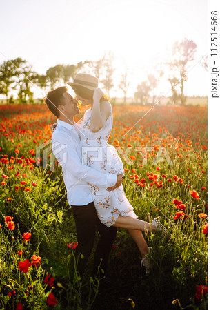 Loving couple in the poppy field at sunset. Enjoying time together. love and lifestyle. Loving couple in the poppy field at sunset. Enjoying time together. love and lifestyle. 112514668