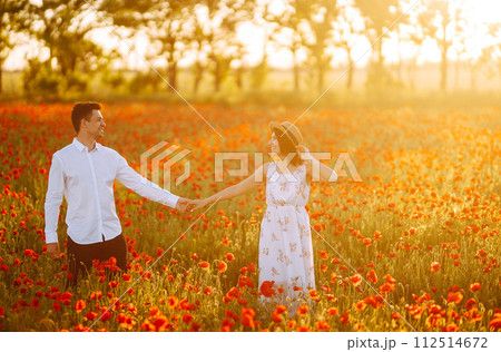 Loving couple in the poppy field at sunset. Enjoying time together. love and lifestyle. 112514672