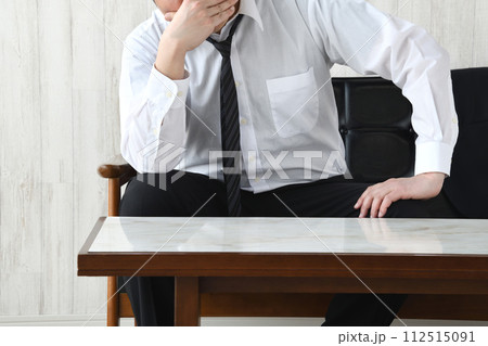 自宅のソファで頭を抱えるビジネスマン 112515091