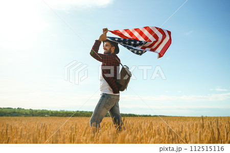 4th of July. American Flag. Traveler with the flag of America. The man in a hat, a backpack, a shirt and jeans. 4th of July. American Flag. Traveler with the flag of America. The man in a hat, a backpack, a shirt and jeans. 112515116