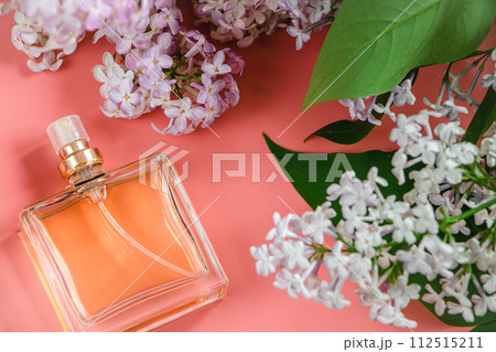Perfume bottle and lilac flowers on pink background. Perfume bottle and lilac flowers on pink background. 112515211