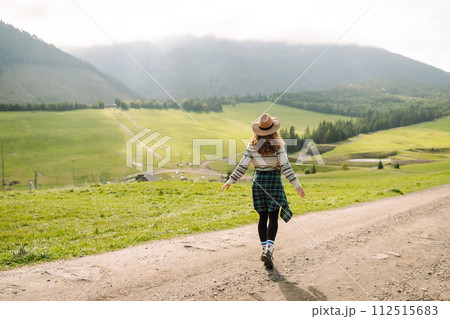 Happy female traveler exploring area in green valley with mountains in background. Concept of nature 112515683