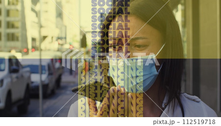 Social distancing text against woman wearing face mask talking on smartphone on the street 112519718