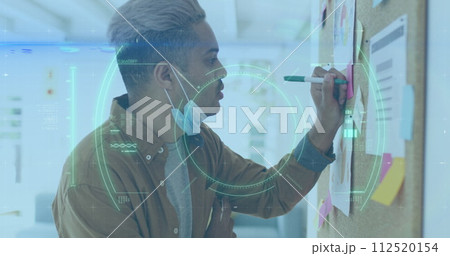 Biracial businessman analyzes data on glass wall in office Biracial businessman analyzes data on glass wall in office 112520154