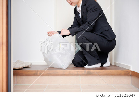 玄関でゴミをまとめるビジネスウーマン 112523047