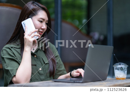 Happy of asian freelance people business female hold pick up smartphone casual working with laptop computer with coffee cup and smartphone in coffee shop like the background,communication concept 112523626