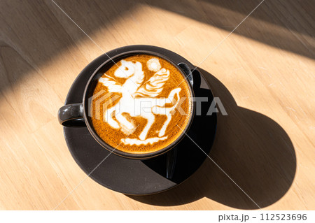 Hot coffee latte with latte art in the form of a horse milk foam in cup mug on wood desk on top view. As breakfast In a coffee shop at the cafe,during business work concept 112523696