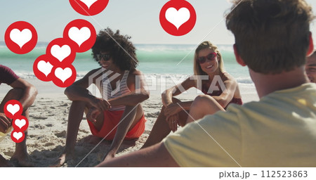 Image of social media heart icons over smiling group of friends on beach Image of social media heart icons over smiling group of friends on beach 112523863
