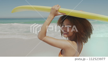 Young African American woman holds a surfboard at the beach 112523977